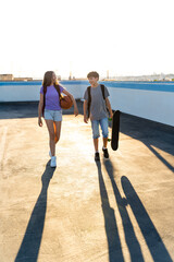 Two Caucasian teenagers walking together outdoors at sunset