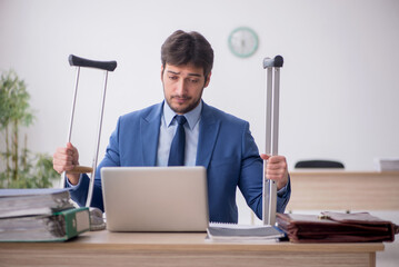 Young male employee after car accident working in the office