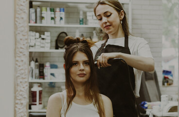 Naklejka premium Portrait of a young girl doing her hair at the hairdresser.