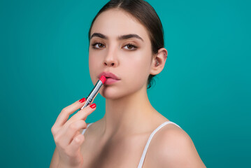 Obraz premium Sexy girl use lipstick, background beauty and fashion, lips appreciation concept. Plump woman lips, isolated on blue studio background.