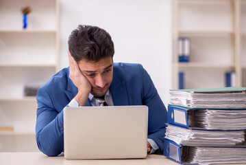 Young male employee and too much work in the office