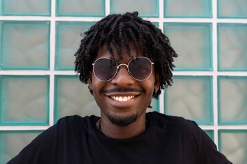 Afro boy with sunglasses smiling at the camera.