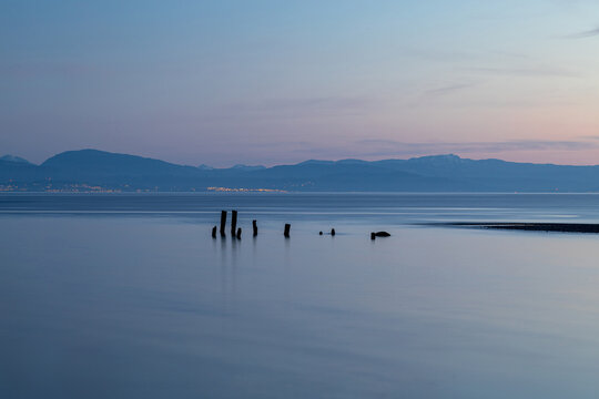 Abandoned cannery pilings at sunset or dusk on the Strait of Georgia or Salish Sea with pink skies looking to Vancouver Island