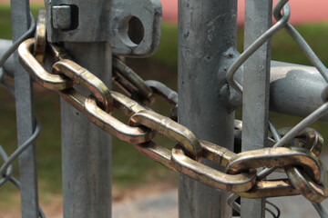 gold chain link locking a silver gated fence shut, close up