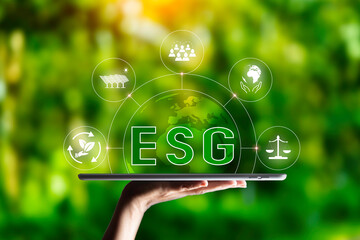 ESG icon in hand on green grass nature background. green energy, eco earth day concept. golden...