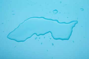 Puddle of water on light blue background, above view