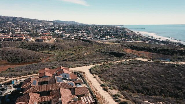 4K drone aerial tracking and stablishing shot of a beach with a pier in California
