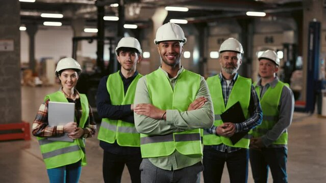 Smiling Face Diverse Team of Machine Technicians in Safety Uniform Standing with Arms Crossed in Warehouse, Looking at Camera at Industrial. Logistic Company. Teamwork Concept