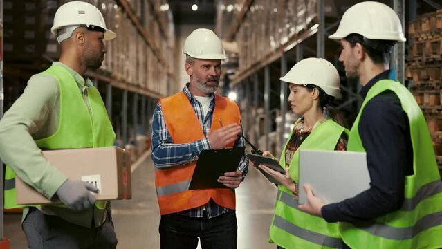 Team of Logistics Center Workers Listen to the Leader and Listening Work Plans. Diverse Team Standing in Warehouse, Engaged in Discussion of New Data Information