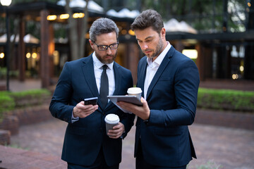 Outdoor business meeting. Business meeting. Businessmen talking. Two businessmen discussing using tablet on coffee break outdoor. Business partners talking.