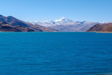 Captured near the tranquil shoreline of Yamdrok Tso lake, this photo showcases the serene beauty of the azure waters and distant snow-capped peaks in the heart of Tibet.