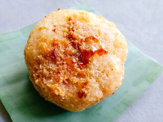 Homemade traditional snack called ondol-ondol or grated cassava filled with brown sugar and then fried on gray background. Close up