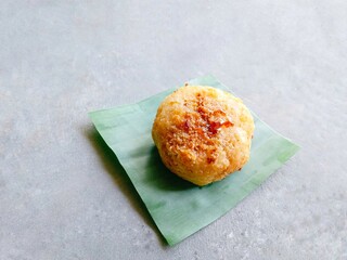 Homemade traditional snack called ondol-ondol or grated cassava filled with brown sugar and then fried on gray background