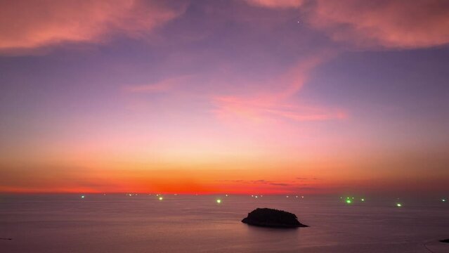 .Aerial hyperlapse The lights from the fishing boat shine beautifully in the sea at dusk..This stunning view captures the beauty of the island as the setting sun casts a pink hue across the sky..