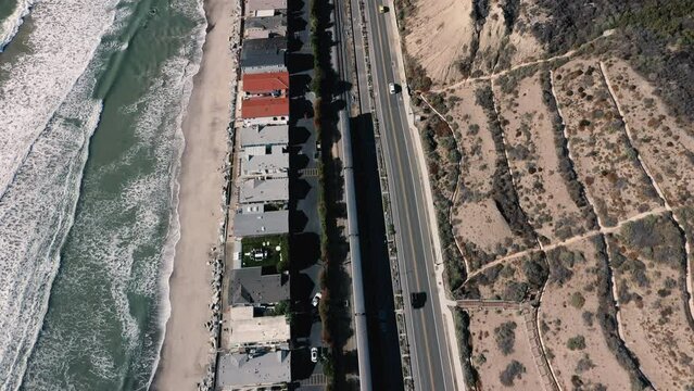 4K drone aerial tracking and stablishing shot of a beach with a pier in California