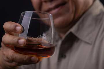 Asian senior man Hand holding glass of whiskey on black background