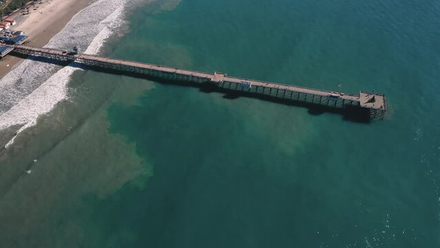 4K drone aerial tracking and stablishing shot of a beach with a pier in California