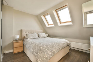 a bed in the corner of a room with wood flooring and two skylights on the top of the roof