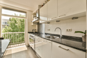 a kitchen with white cabinets and black granite counter tops in front of the window looking out onto the street outside