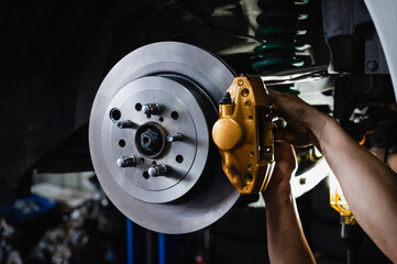 Sport car brake repair and service in garage shop. auto mechanic installing new rear brake pads and brake rotors.