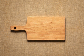 Handmade cherry wood cutting board on burlap. Empty wooden chopping board background.
