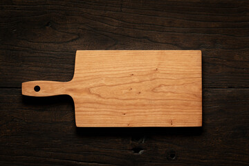 Handmade cherry wood cutting board on black solid wood table top. Empty wooden chopping board background. wooden cutting board.