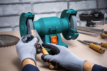 Man Sharpening Work Tool, Chisel On Grinder In Workshop.