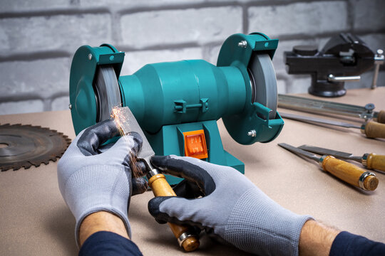 Man Sharpening Work Tool, Chisel On Grinder In Workshop.