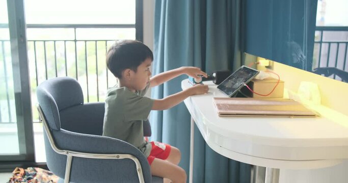 Kindergarten asian boy watching cartoon on tablet in hotel room travel vacation trip