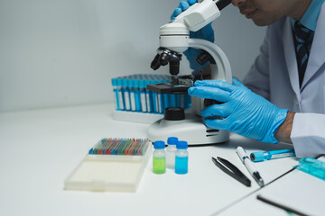 Asian scientist looking at a microscopic sample of experimental cyan is doing an in vitro vaccine experiment in a science lab. medical research concept.