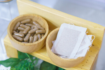 herbal capsule in wooden cup with herbal tea for spa treatment or relaxation