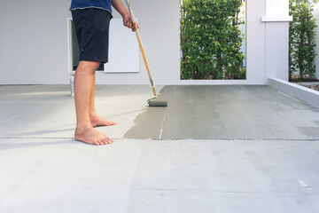 Worker and renovation work. To using roller painting mortar cement or finishing material for repair crack, skim coat or improvement surface of concrete pavement floor or slab for driveway or garage.
 - obrazy, fototapety, plakaty