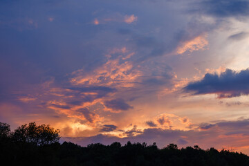 Obraz premium Colorful sunset and clouds in Wisconsin during summer with tree line silhouette 