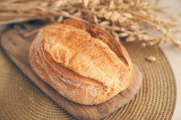Close-up of rustic wheat bread. Freshly baked round bread with a golden crust on a wooden board. With space to copy. High quality photo