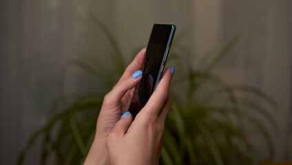 Womans hands is using smartphone, writing a message, browsing social networks.