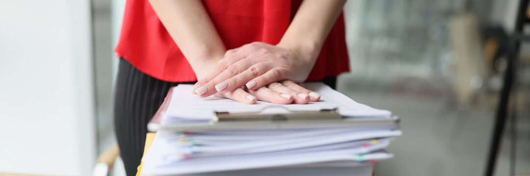 Female hands rest on a stack of folders on the table