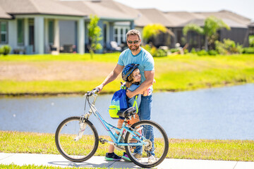 father and son on bicycle at fathers day. active father setting a example for fathers son. fathers parenting with son outdoor. Fatherly love and care. childhood of son supported by fathers care