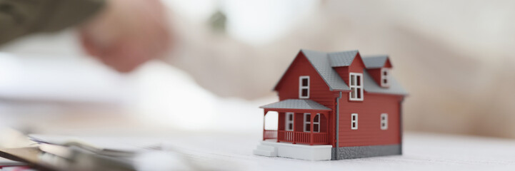 A plastic model of a red house on the table, closeup