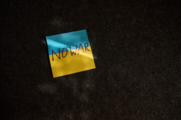 The sticker in the form of the Ukrainian flag lies. on a dark surface and a ray of sunlight falls...