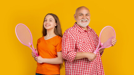 smiling child with grandfather with badminton racket on yellow background