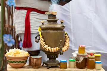 An old Russian samovar with bagels and honey products on the table.