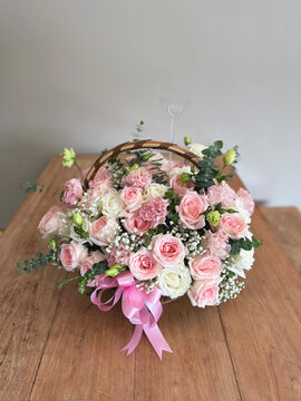 Beautiful colourful blossoming basket of fresh blossoming flowers, close up view. White and pink rose boquete on wooden table