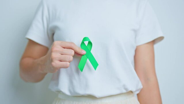 Woman holding green Ribbon for world Lymphoma Awareness September month, world Mental Health Day, Liver, Gallbladders, bile duct, cervical, kidney Cancer. Healthcare and world cancer day concept
