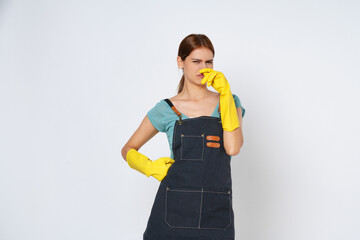 Young woman wearing yellow rubber gloves covered her nose with her hand an unpleasant smell isolated on white background.