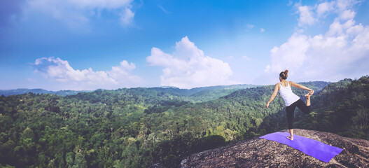 Asian women relax in the holiday. Play if yoga. On the Moutain rock cliff. Nature of mountain forests in Thailand