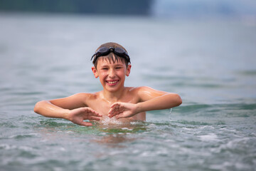 A boy in swimming goggles swims in the sea.