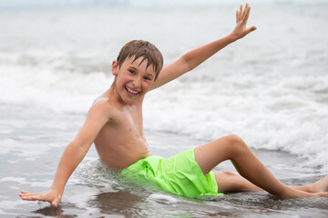 Fototapeta na wymiar Happy boy swims at the sea, looks into the camera. Summer rest.