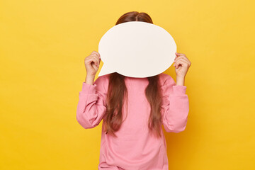 Unrecognizable little girl with long hair covering face behind empty speech bubble wearing pink...