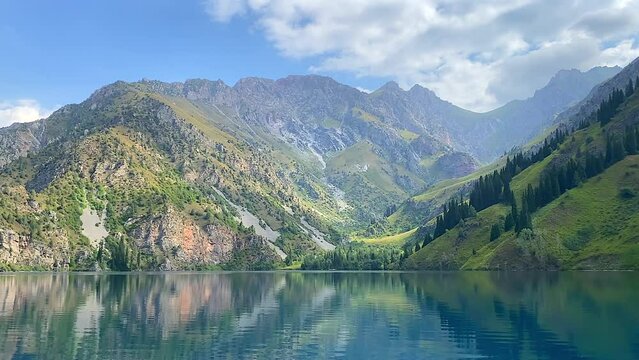 The picturesque lake of Sary Chelek. Amazing untouched nature of Kyrgyzstan. State Biosphere Reserve. Green hills and rocky mountains.