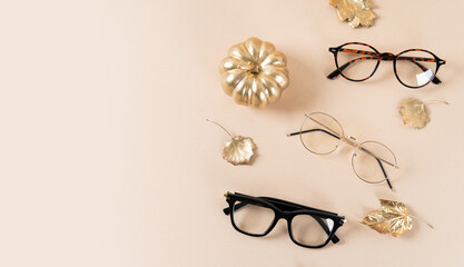 Eyewear and glasses sale concept. Trendy glasses on beige background with a pumpkin and golden...